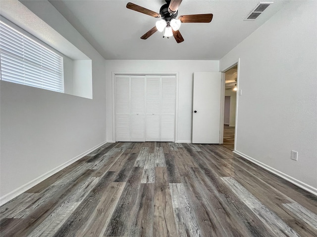 unfurnished bedroom with dark hardwood / wood-style floors, a closet, and ceiling fan