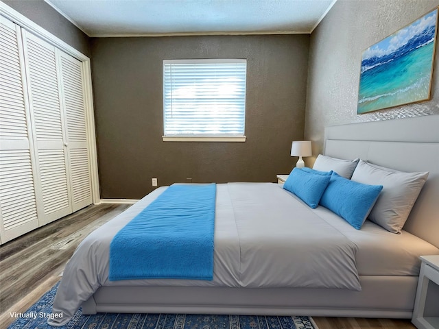 bedroom featuring hardwood / wood-style floors, crown molding, and a closet