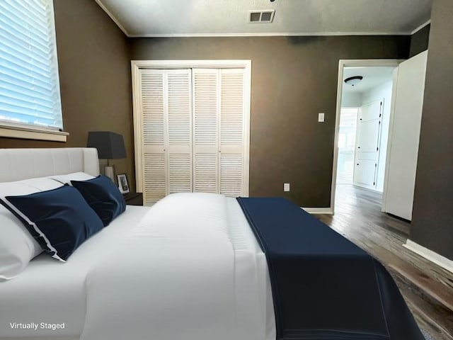 bedroom with ornamental molding, hardwood / wood-style floors, and a closet