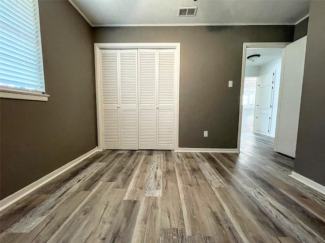 unfurnished bedroom with crown molding, hardwood / wood-style flooring, and a closet