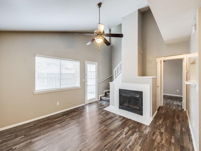 unfurnished living room with baseboards, a tile fireplace, ceiling fan, stairway, and wood finished floors