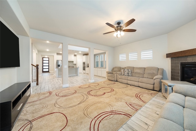 living room with decorative columns, light hardwood / wood-style flooring, and ceiling fan