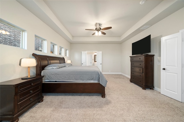 carpeted bedroom featuring a tray ceiling and ceiling fan