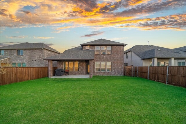 back house at dusk with a lawn and a patio