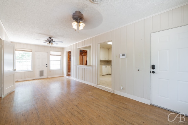 unfurnished living room featuring ceiling fan, a textured ceiling, and light hardwood / wood-style flooring