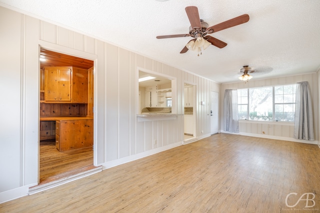 unfurnished living room featuring light hardwood / wood-style floors, ornamental molding, a textured ceiling, and ceiling fan