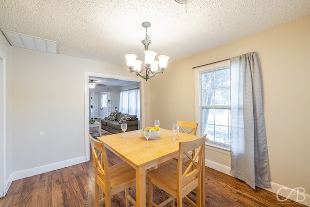 dining space with a textured ceiling, ceiling fan with notable chandelier, dark hardwood / wood-style flooring, and a healthy amount of sunlight