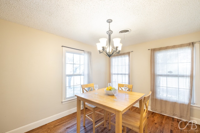 dining space with a notable chandelier, dark hardwood / wood-style floors, and a textured ceiling