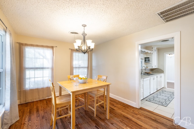 dining area with an inviting chandelier, hardwood / wood-style floors, sink, and a textured ceiling