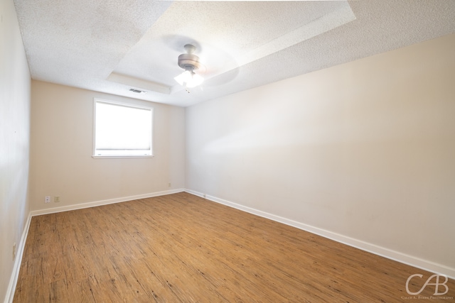 spare room featuring hardwood / wood-style floors, a raised ceiling, and a textured ceiling