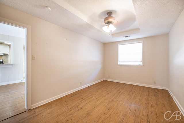 spare room featuring light wood-type flooring, ceiling fan, and a textured ceiling