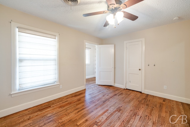 spare room with light hardwood / wood-style floors, a textured ceiling, and ceiling fan