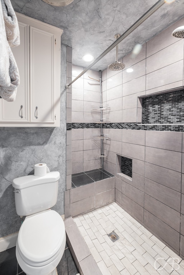 bathroom featuring tile walls, tiled shower, and toilet