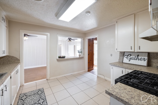 kitchen with ornamental molding, a textured ceiling, light tile patterned floors, and white cabinets