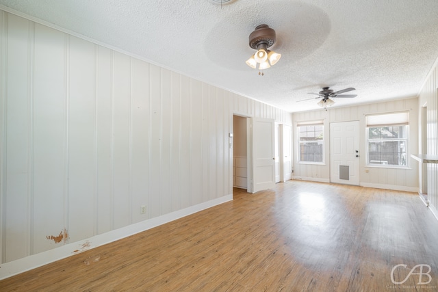 empty room with ceiling fan, a textured ceiling, and light hardwood / wood-style floors