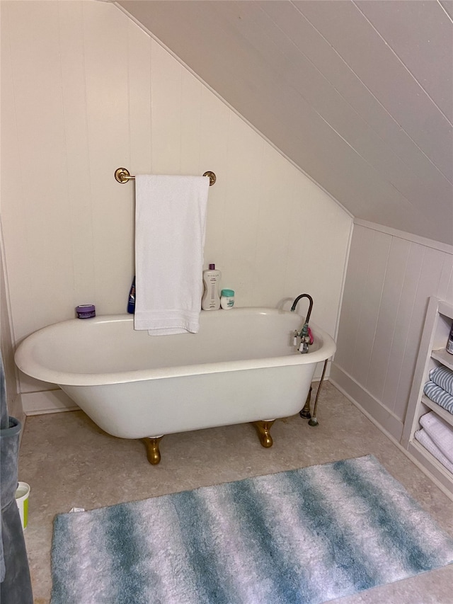 bathroom featuring a bath, wood walls, and vaulted ceiling