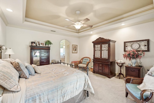 carpeted bedroom with ceiling fan, a tray ceiling, and ornamental molding