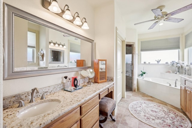 bathroom featuring ceiling fan, plenty of natural light, a tub to relax in, and vanity