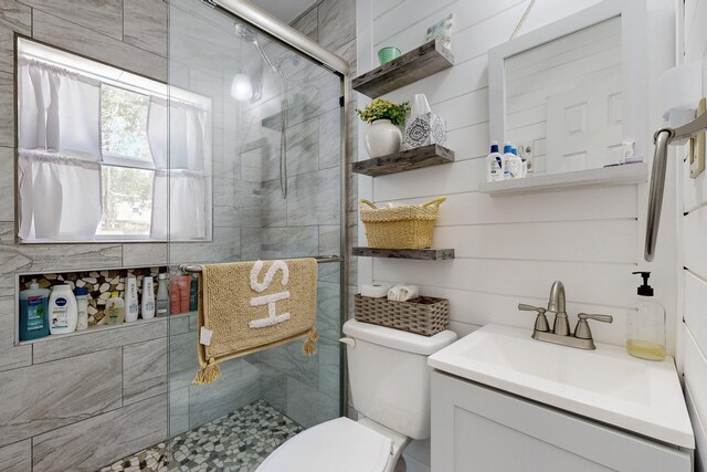 bathroom featuring vanity, a shower with shower door, and toilet