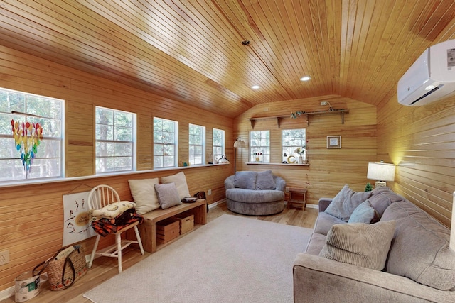 living room with a wall mounted AC, light hardwood / wood-style flooring, vaulted ceiling, and a wealth of natural light