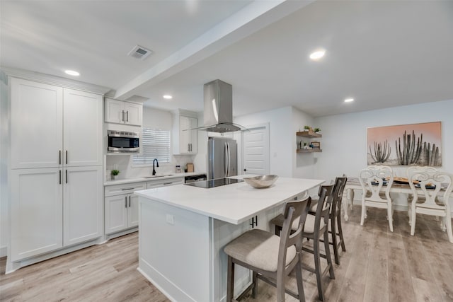 kitchen with white cabinetry, island range hood, light wood-type flooring, and appliances with stainless steel finishes