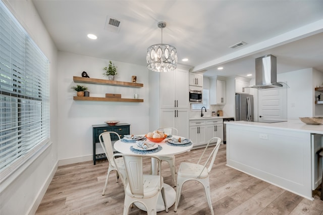 dining area featuring an inviting chandelier, light hardwood / wood-style flooring, and sink