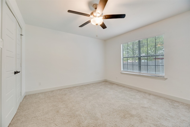 spare room with ceiling fan and light colored carpet