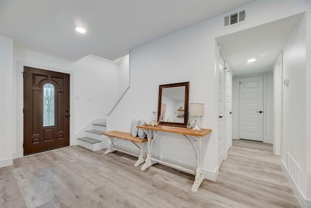 foyer entrance with stairway, light wood-type flooring, visible vents, and baseboards