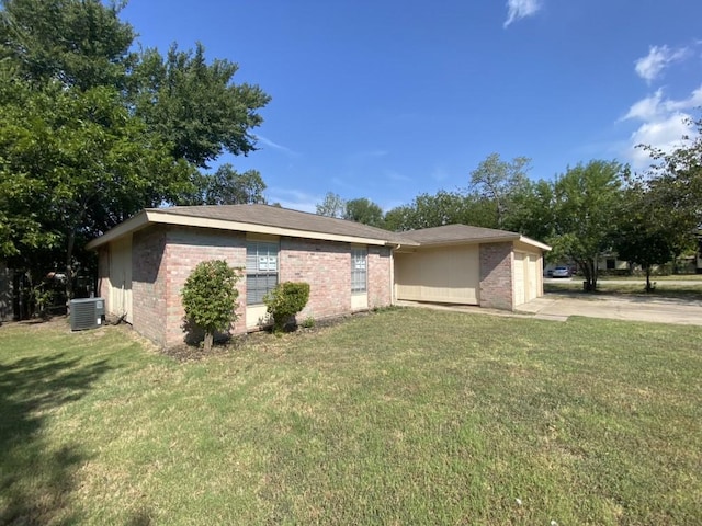 view of front of home with a front lawn, cooling unit, brick siding, and a garage