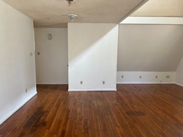 empty room with dark hardwood / wood-style flooring and a textured ceiling