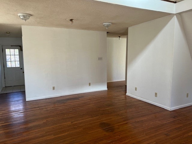 unfurnished room with a textured ceiling and dark hardwood / wood-style floors