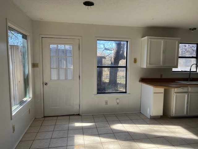 kitchen featuring white cabinets, light tile patterned floors, plenty of natural light, and sink