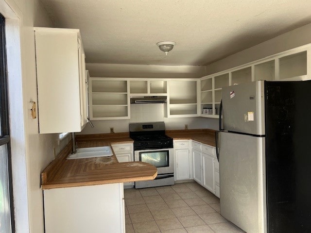 kitchen featuring white cabinetry, sink, stainless steel appliances, light tile patterned floors, and exhaust hood