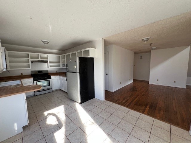 kitchen with stainless steel appliances, white cabinetry, and light tile patterned flooring