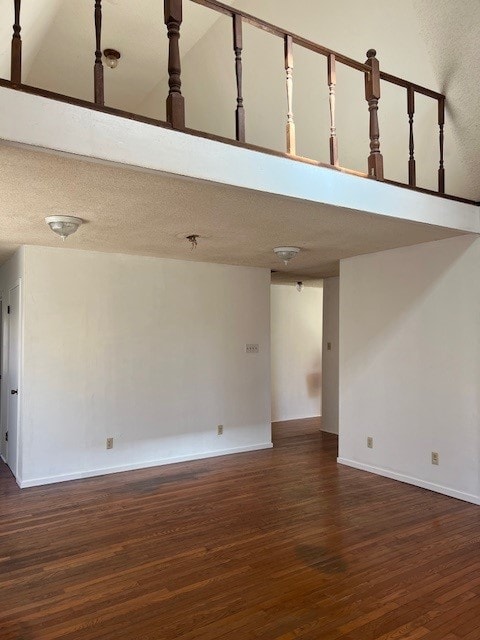 empty room with a high ceiling and dark hardwood / wood-style flooring