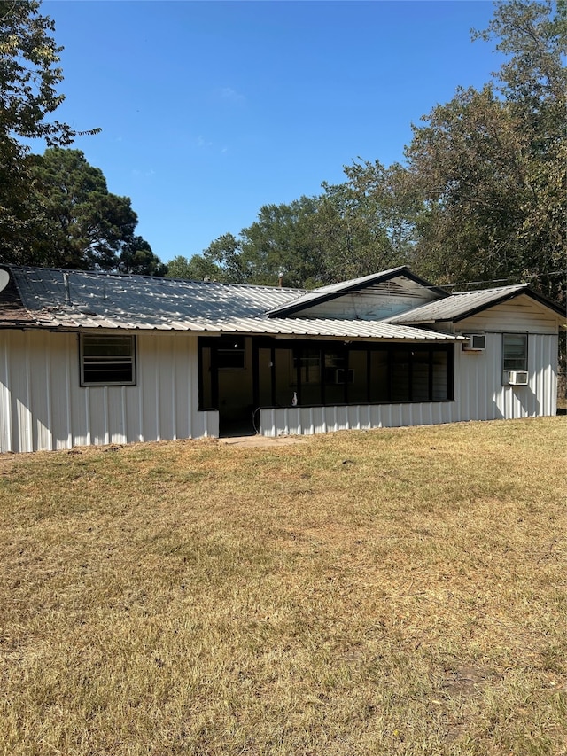 back of property with a wall unit AC and a yard