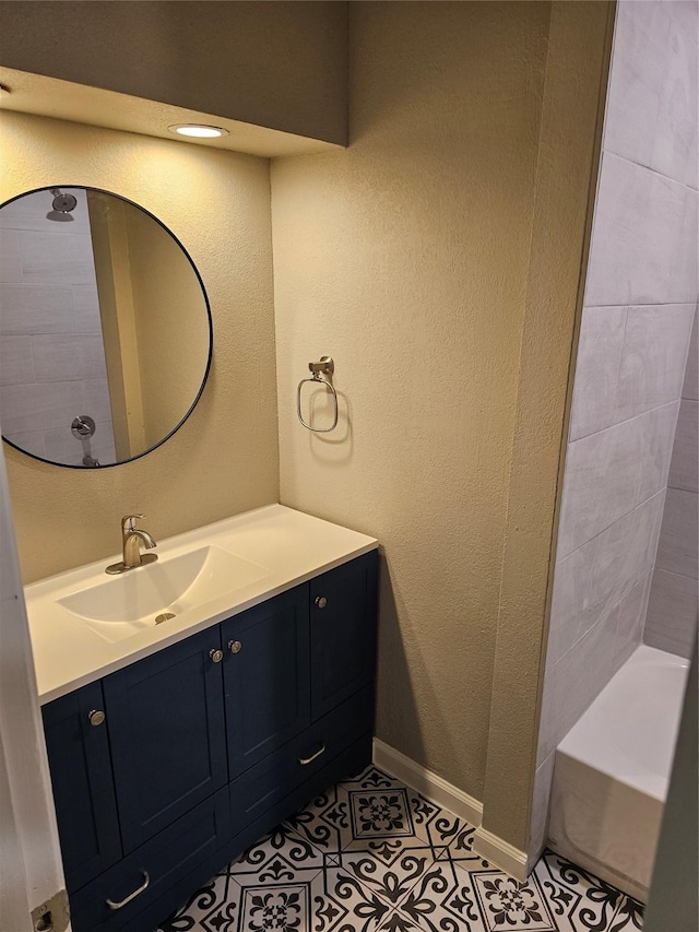 full bathroom with baseboards, a textured wall, tile patterned floors, a bathtub, and vanity