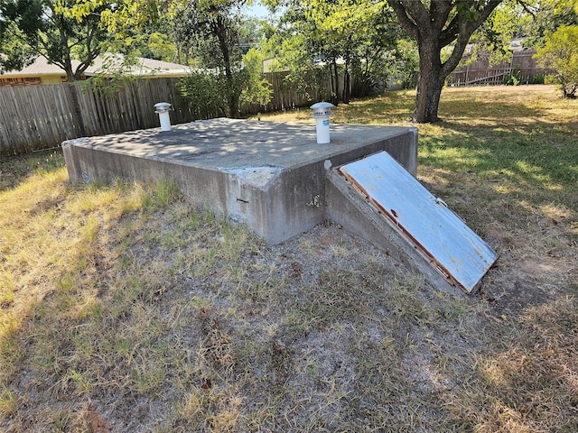 entry to storm shelter featuring a fenced backyard and a lawn