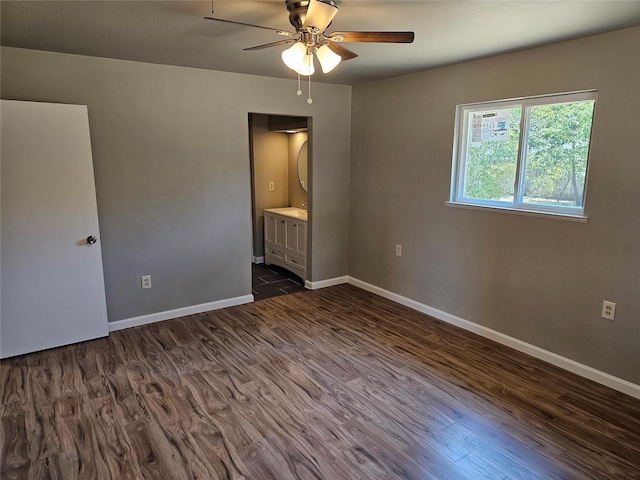 unfurnished bedroom featuring dark wood-style floors, ceiling fan, ensuite bathroom, and baseboards