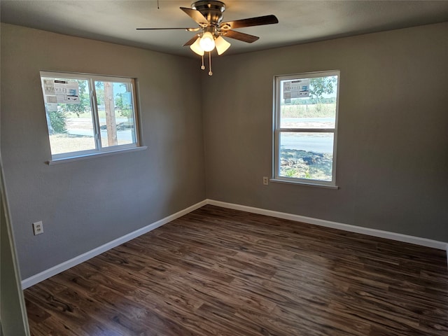 empty room featuring dark wood-type flooring, plenty of natural light, baseboards, and a ceiling fan