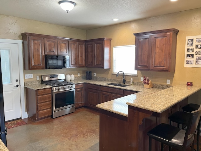 kitchen featuring gas range, sink, kitchen peninsula, and a kitchen bar