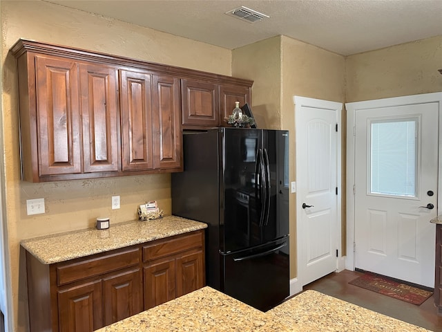 kitchen with light stone counters and black refrigerator