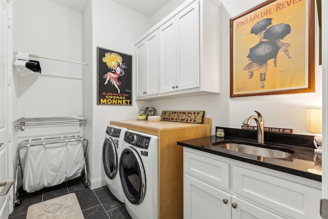 washroom with sink, dark tile patterned floors, cabinets, and washer and dryer