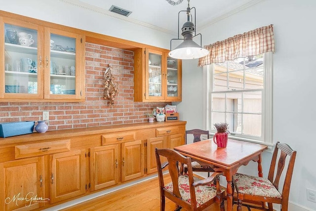 dining room with light wood-type flooring and ornamental molding