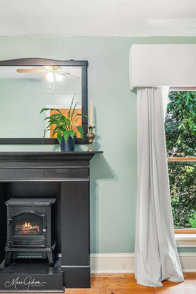 details with ceiling fan, hardwood / wood-style flooring, and a wood stove