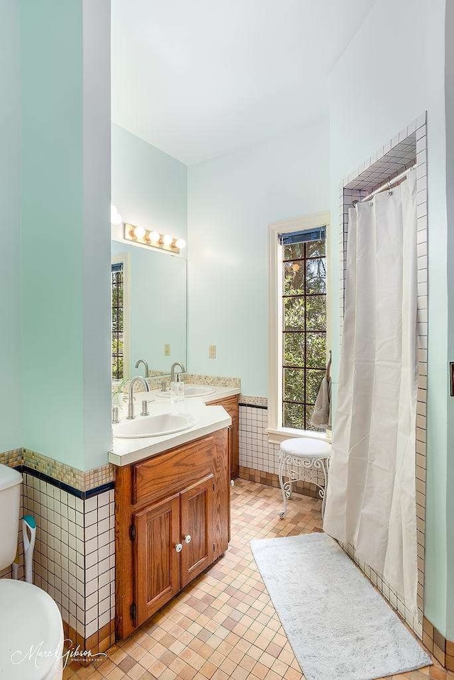 bathroom with tile patterned floors, vanity, tile walls, toilet, and walk in shower