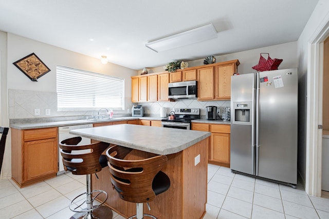 kitchen featuring a kitchen breakfast bar, backsplash, a center island, light tile patterned floors, and stainless steel appliances