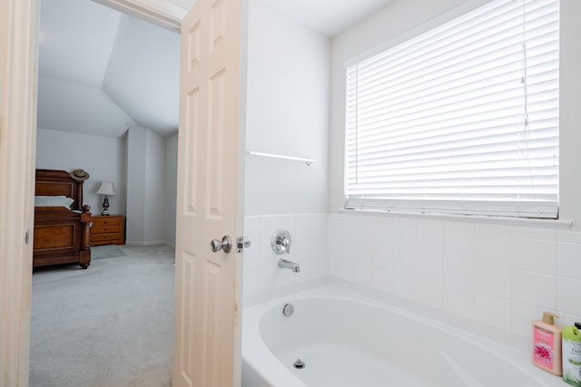 bathroom with vaulted ceiling and a tub to relax in