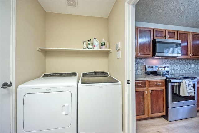 laundry area featuring a textured ceiling, light wood-style flooring, laundry area, separate washer and dryer, and visible vents