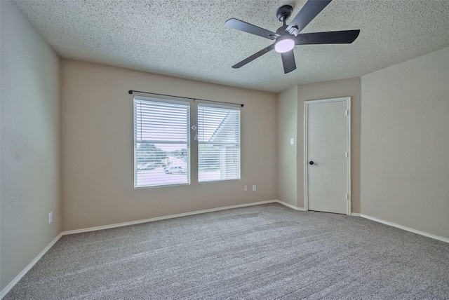 carpeted spare room with a textured ceiling, a ceiling fan, and baseboards